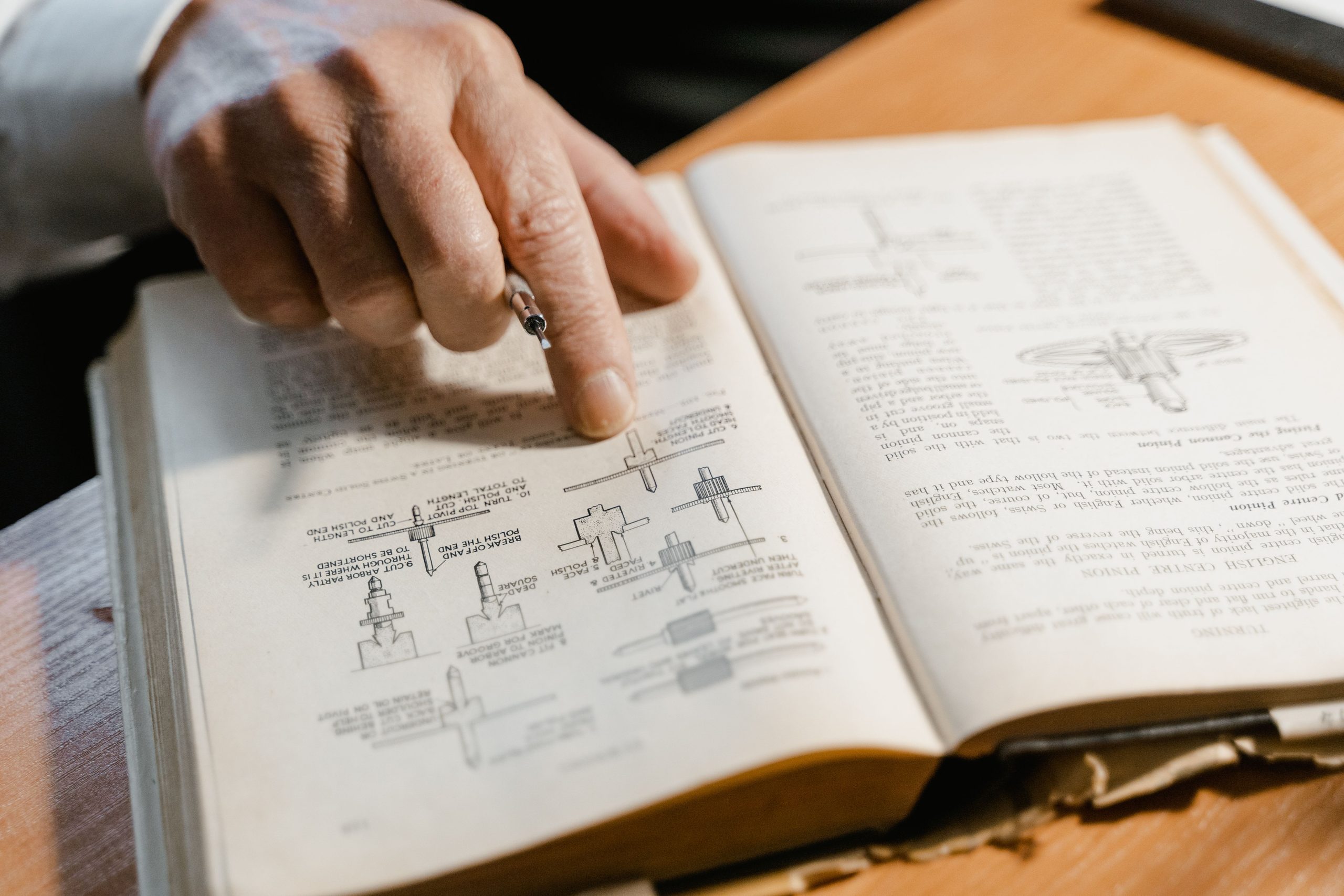 photo by tima-miroshnichenko showing a hand keeping its place over a line of text in a book from a freemason reading list